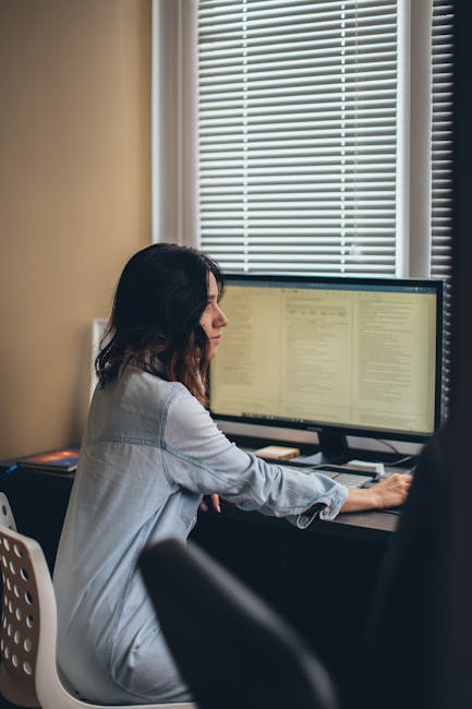 Person taking a break from computer screen looking out window with natural lighting